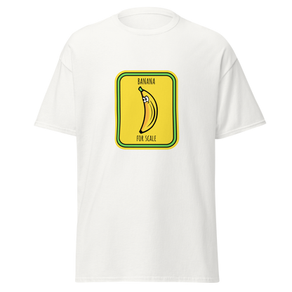 Valkoinen unisex huumoripaita, jonka keskellä on kirkkaankeltainen, liikennemerkin muotoinen painatus. Kuvassa sarjakuvatyylinen banaani, jonka yläosassa on silmät. Tekstit "BANANA" ylhäällä ja "FOR SCALE" alhaalla – kielletään kaikki